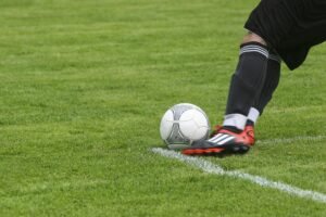 Dynamic shot of a soccer player kicking the ball on a grassy field, showcasing fast-paced sports action.