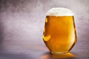 A modern glass filled with cold craft beer on a grey background, perfect for beverage ads.