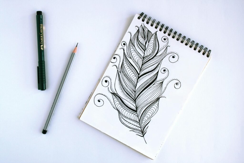 Artistic feather sketch with pen and pencil on sketchpad, showcasing intricate details.
